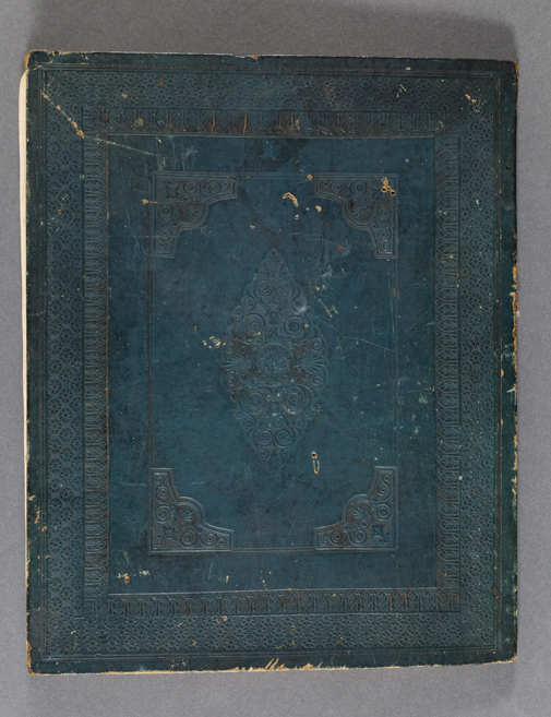 This image is a photograph of a passbook cover. The photograph shows the front cover of the Félix-Émile Taunay’dspassbook, brother of Aimé-Adrien Taunay, in blue. The object has a worn appearance and abstract details in low relief volute separated by also embossed frames.